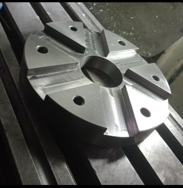 Pieza metálica maquinada con orificios y ranuras